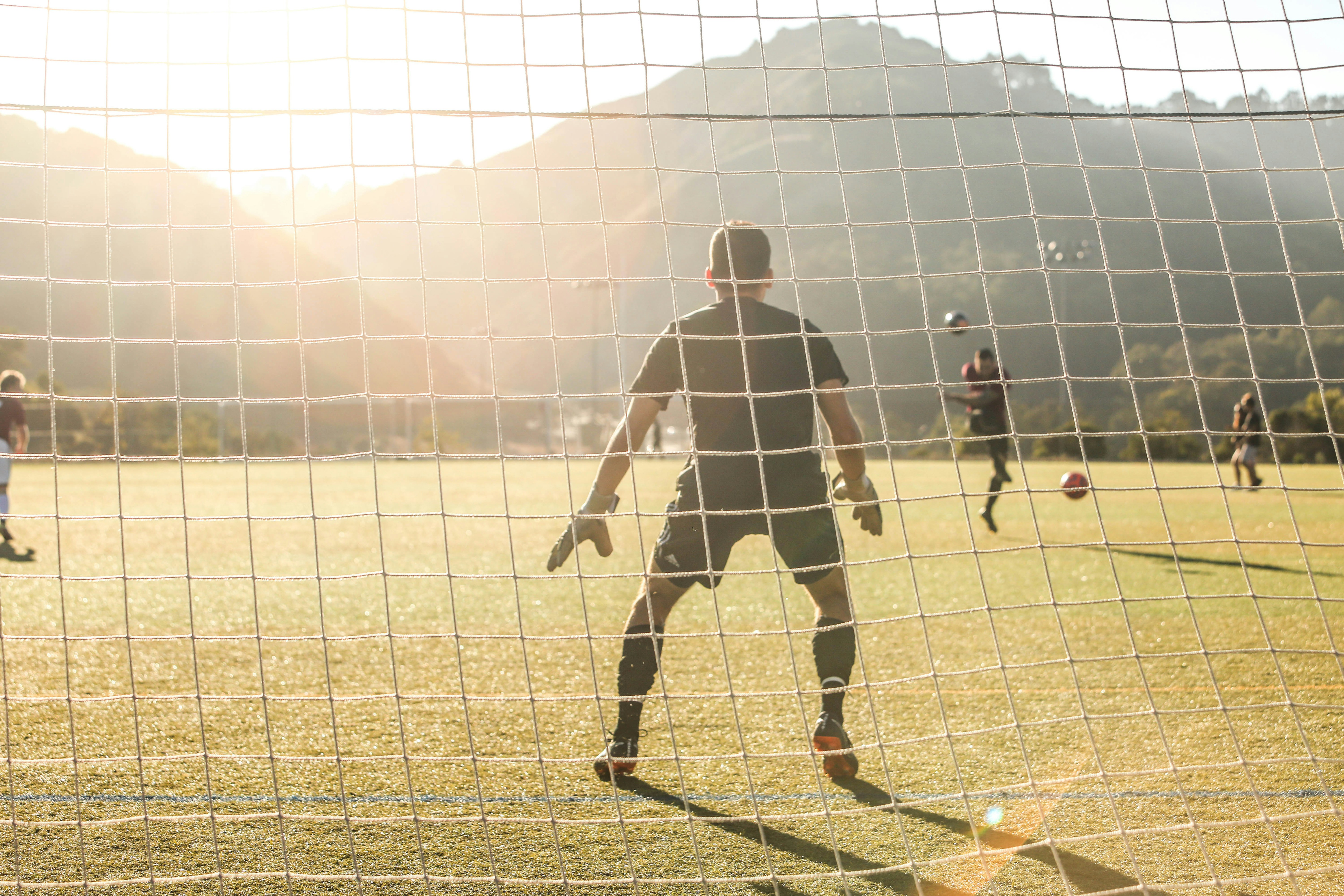 Soccer goalie, sunshine coming up over mountains