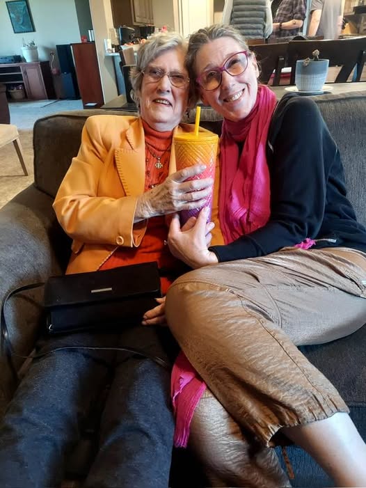 mother and daughter leaning together wearing bright colors